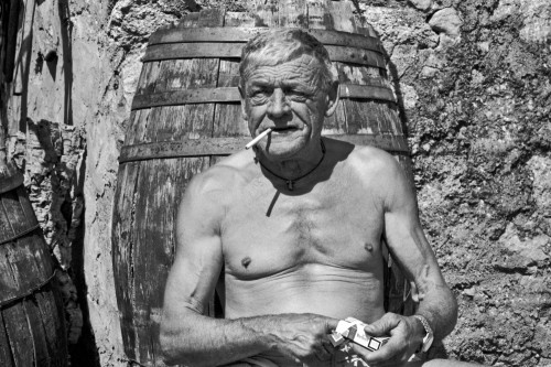 G.P.Località La Macciona - Comune di Aglientu Stazzu La Macciona. Ritratto del proprietario con vecchi attrezzi di uso agricolo alle spalle